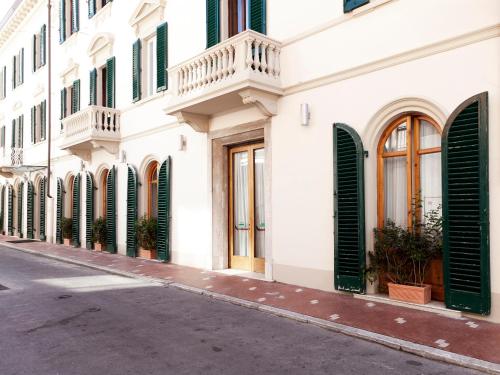a white building with green shutters on a street at Hotel Savoia e Campana in Montecatini Terme