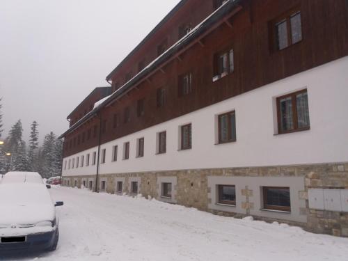 a snow covered building with a car parked next to it at Apartmán Špičák Sruby in Špičák