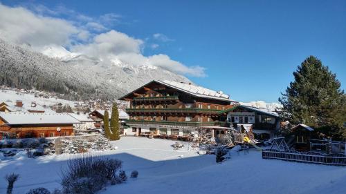 a large building in the snow in front of a mountain at Familien- & Vitalhotel Auenhof in Fulpmes