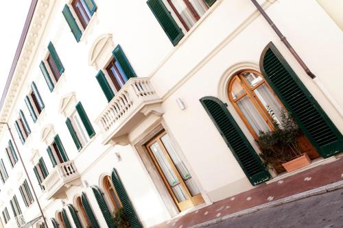 a white building with green shuttered windows at Hotel Savoia e Campana in Montecatini Terme