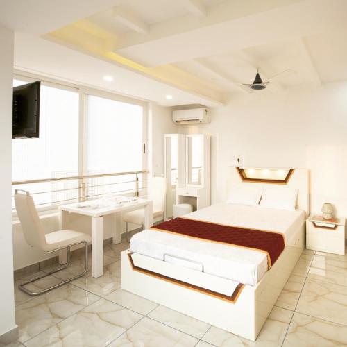 a white bedroom with a bed and a desk at Rahul Residency in Mangalore