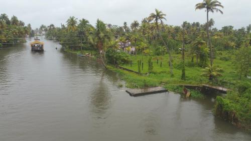 a boat traveling down a river with palm trees at ABRU'S Holidays International Travelers in Alleppey