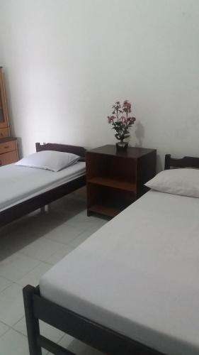 ein Schlafzimmer mit 2 Betten und einem Tisch mit Blumen darauf in der Unterkunft Penginapan Kofiyau in Sorong