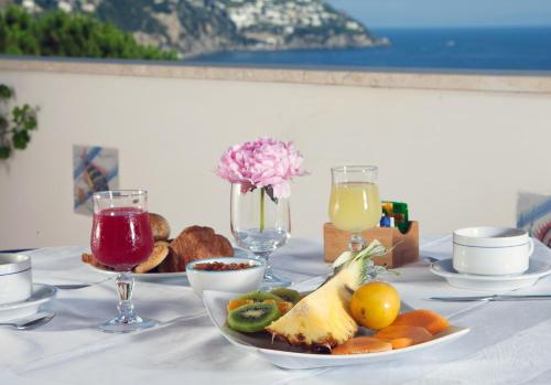 einen Tisch mit einem Teller mit Essen und Gläsern Wein in der Unterkunft Hotel Vittoria in Positano