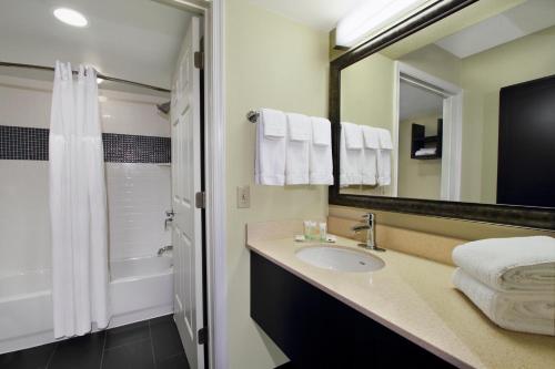 ein Bad mit einem Waschbecken, einer Dusche und einem Spiegel in der Unterkunft Staybridge Suites Tysons - McLean, an IHG Hotel in McLean