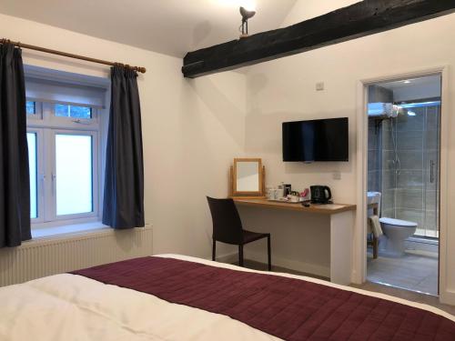 a bedroom with a bed and a desk and a television at Bex Rooms in Worthing