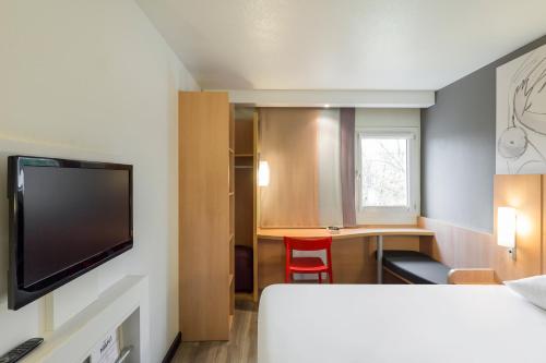 a room with a bed and a desk with a television at ibis Paris Meudon Velizy in Meudon