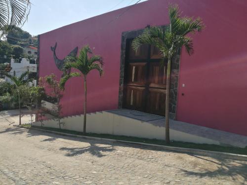 a pink building with palm trees in front of it at Casa de la Ballena in Sayulita