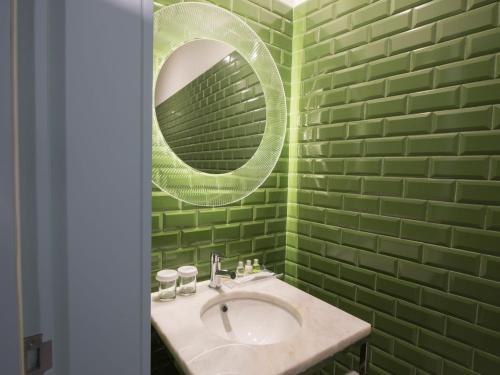 a green bathroom with a sink and a mirror at Apartamentos The Arc Carrís in Porto