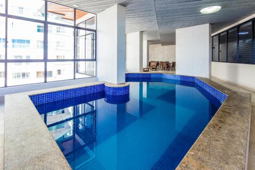 a large pool with blue water in a building at Hotel D'sintra in Balneário Camboriú