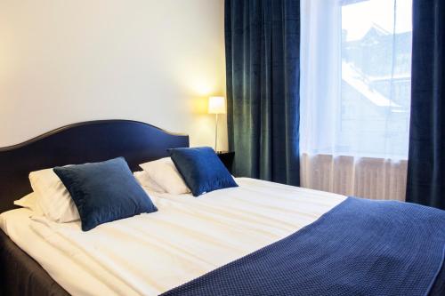 a bed with two blue pillows on it with a window at Best Western Hotel Trollhattan in Trollhättan