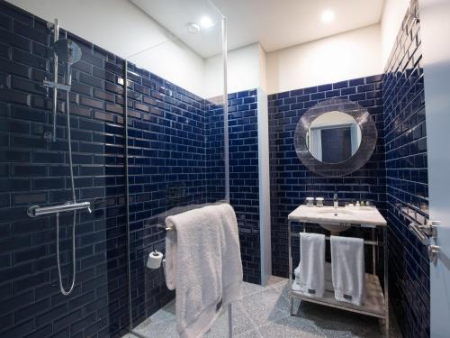a blue tiled bathroom with a sink and a mirror at Apartamentos The Arc Carrís in Porto