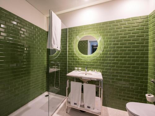 a green bathroom with a sink and a mirror at Apartamentos The Arc Carrís in Porto
