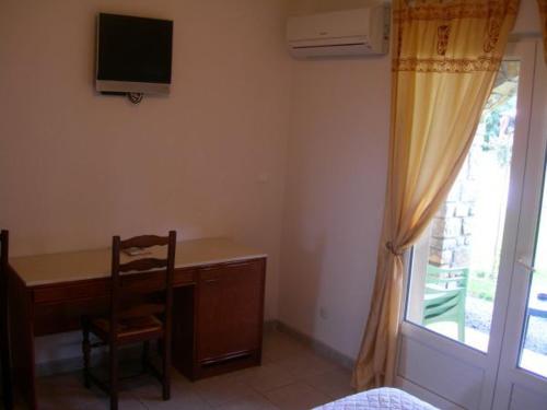 a bedroom with a desk and a chair and a window at Hôtel de la Madeleine Anduze in Tornac