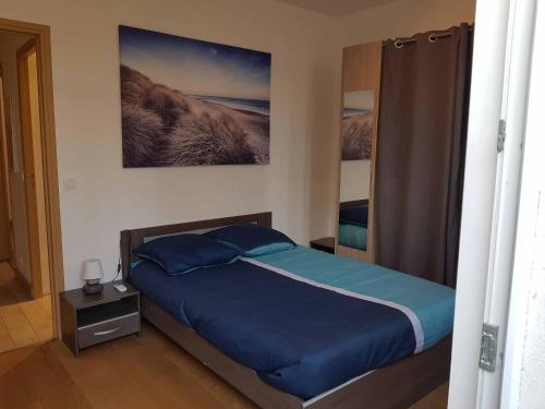a bedroom with a bed with blue sheets and a painting on the wall at les orangers in Cannes