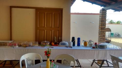 a long table with chairs and a table with food on it at Dáriu's Pousada in Prea