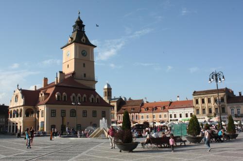 a building with a clock tower in a town square at Casa Schei in Braşov