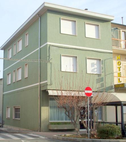 a green building with a red stop sign in front of it at Hotel Cucciolo in Donoratico