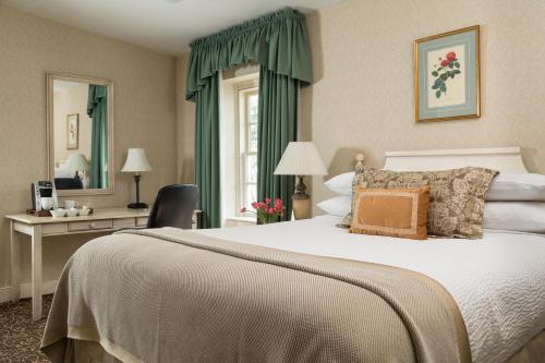 a bedroom with a bed and a desk and a window at Linden Row Inn in Richmond