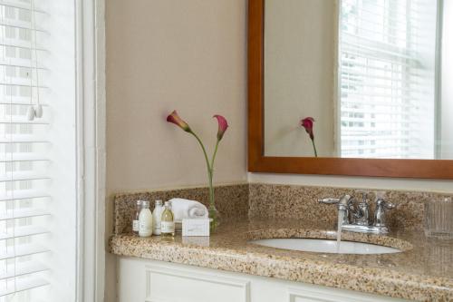 a bathroom with a sink and a mirror and flowers at Linden Row Inn in Richmond