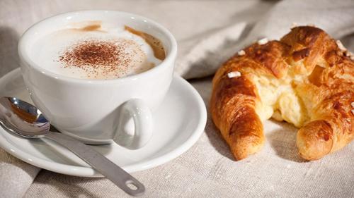 a cup of coffee and a croissant on a table at Obelisco in Naples