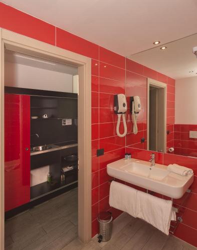 a red bathroom with a sink and a phone on the wall at Blue Shades Hotel in Pisa