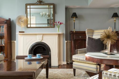 a living room with a fireplace and a chair and a mirror at Linden Row Inn in Richmond