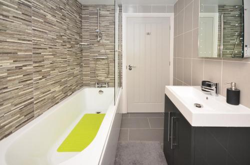 een badkamer met een bad, een wastafel en een douche bij The Stables at Flash Farm House in Crewe