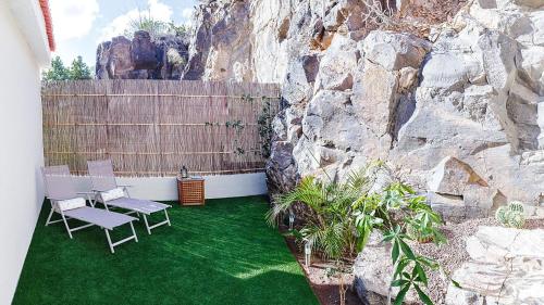 a patio with two chairs and a rock wall at Time To Experience in Salobre