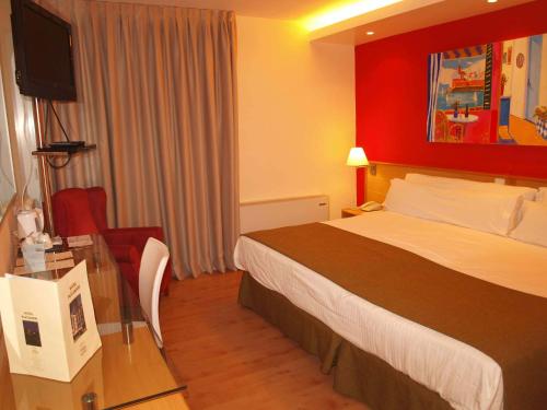 a hotel room with a bed and a desk with a television at Platjador in Sitges