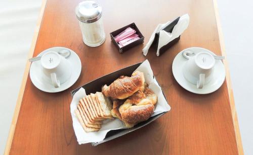 una mesa con un plato de pastas y tazas de café en Hotel Oasis en Mar del Plata