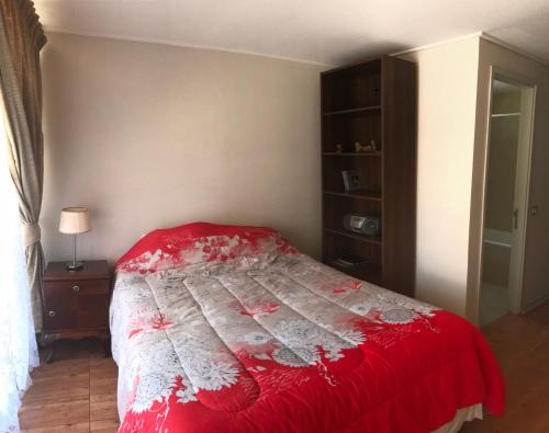 a bedroom with a bed with a red blanket at Depto Marina Poniente in Viña del Mar