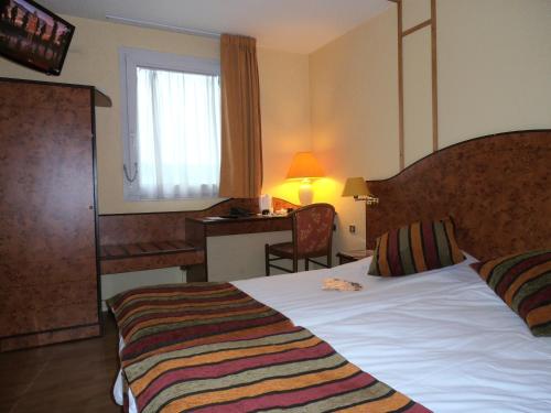Habitación de hotel con cama, escritorio y ventana en Logis Cottage Hôtel en Calais