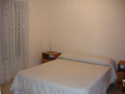 1 dormitorio con 2 camas y ventana con lámpara en Glaniad Apartments, en Puerto Madryn