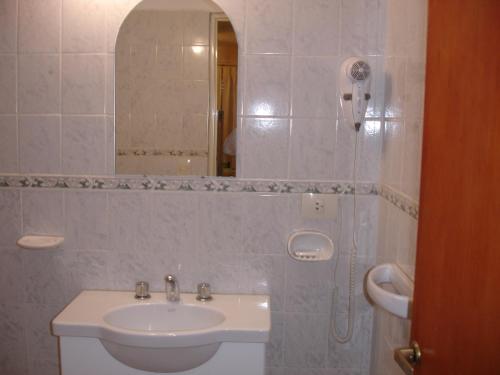 Un baño blanco con lavabo y espejo. en Glaniad Apartments, en Puerto Madryn