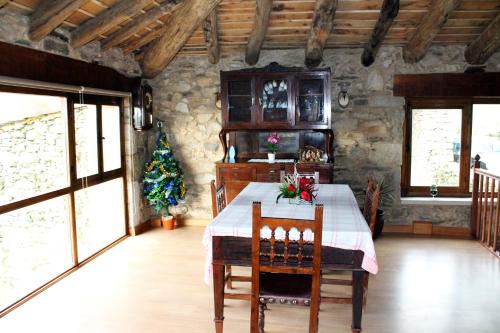 a dining room with a table with chairs and a christmas tree at Casiña de Campo in Ferreiros