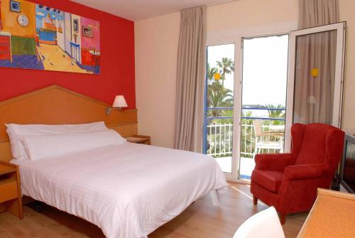 
a hotel room with a bed, chair and a window at Platjador in Sitges
