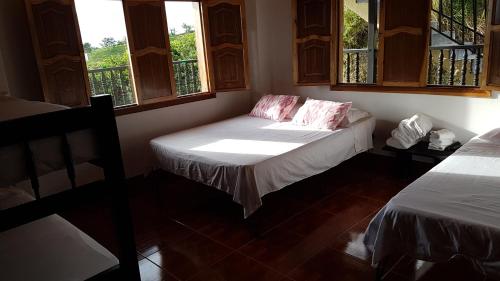 a room with two beds and two windows at Alojamiento Rural Bellavista in Filandia