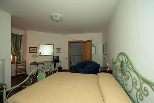 a bedroom with a bed and a blue chair at Albergo Villa Cristina in Spoleto