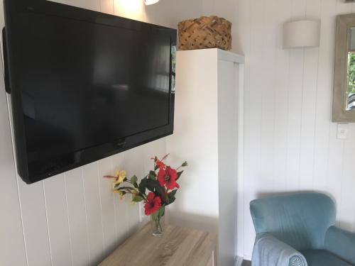 a television hanging on a wall with a vase of flowers at Stay Kerikeri in Kerikeri