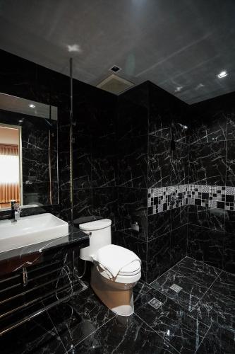 a black bathroom with a toilet and a sink at Hap@sathorn in Bangkok