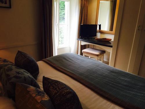 1 dormitorio con cama y escritorio con espejo en Mason's Arms en Bowland Bridge