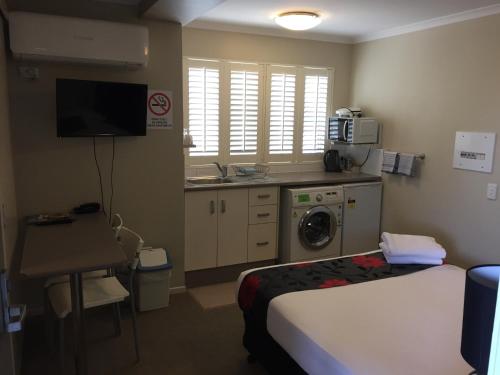 a hotel room with a bed and a kitchen with a washing machine at Brisbane Street Studios in Brisbane