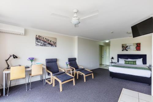 a bedroom with a bed and a desk and chairs at The Wellington Apartment Hotel in Brisbane