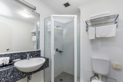 a white bathroom with a sink and a toilet at The Wellington Apartment Hotel in Brisbane