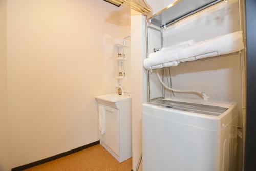 uma pequena casa de banho branca com máquina de lavar e secar roupa em Hana Botan em Quioto