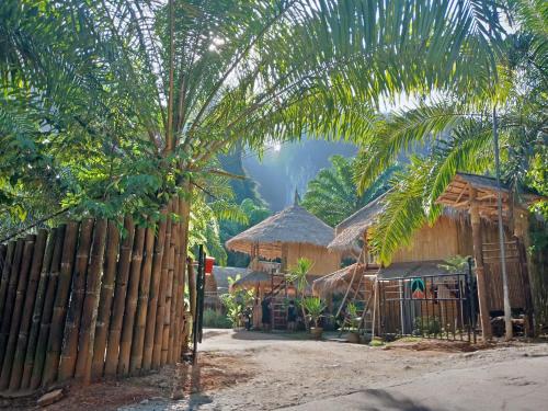 a house with a fence and a palm tree at KRABI BAMBOO KINGDOM at AOLUEK PARADISE in Ao Luk