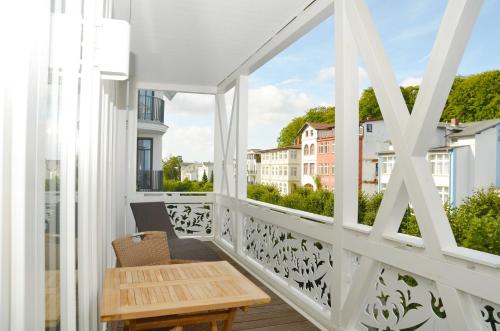 a white balcony with a wooden table and a window at Villa "Johanna" Sellin - WG12 mit Kamin und zwei Balkonen in Ostseebad Sellin