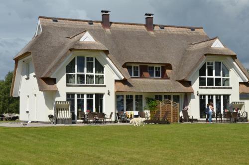 a large house with a dog walking in front of it at Reethus am Strand - Haushälfte 2 mit Kamin, Sauna in Lobbe