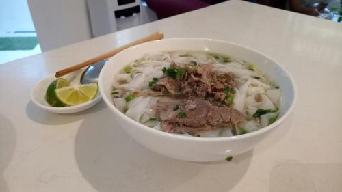 een kom soep met vlees en noedels op een tafel bij Dinh Ami Hanoi Hotel in Hanoi